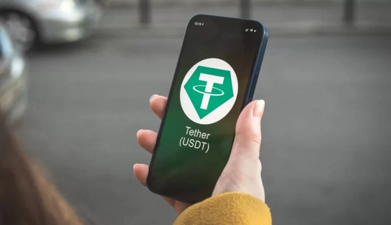 Someone holding a smartphone with the Tether logo displayed on screen.