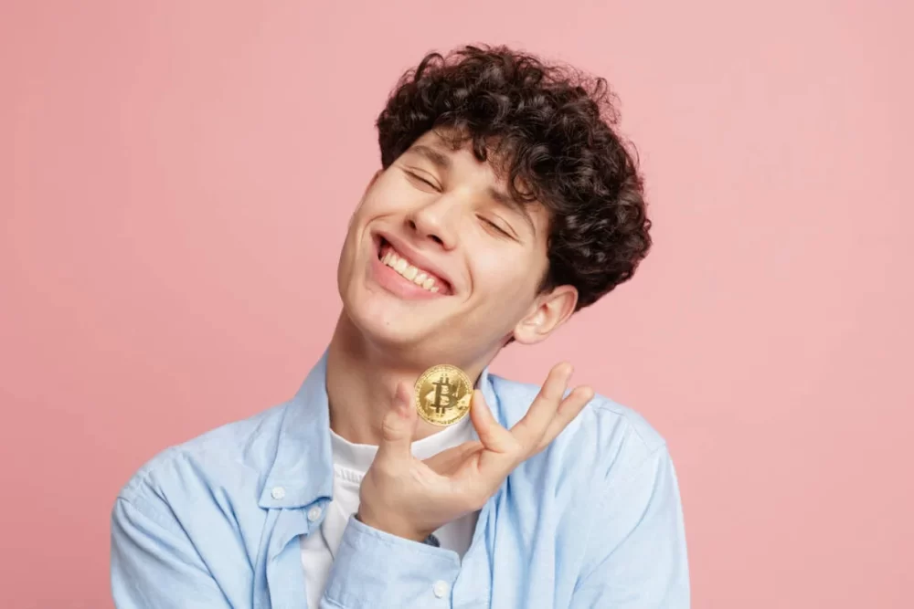 A man joyfully holding a golden bitcoin.