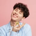 A man joyfully holding a golden bitcoin.
