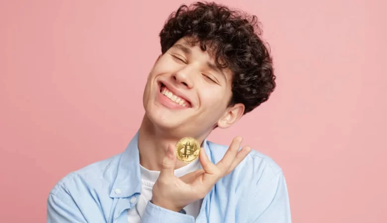 A man joyfully holding a golden bitcoin.
