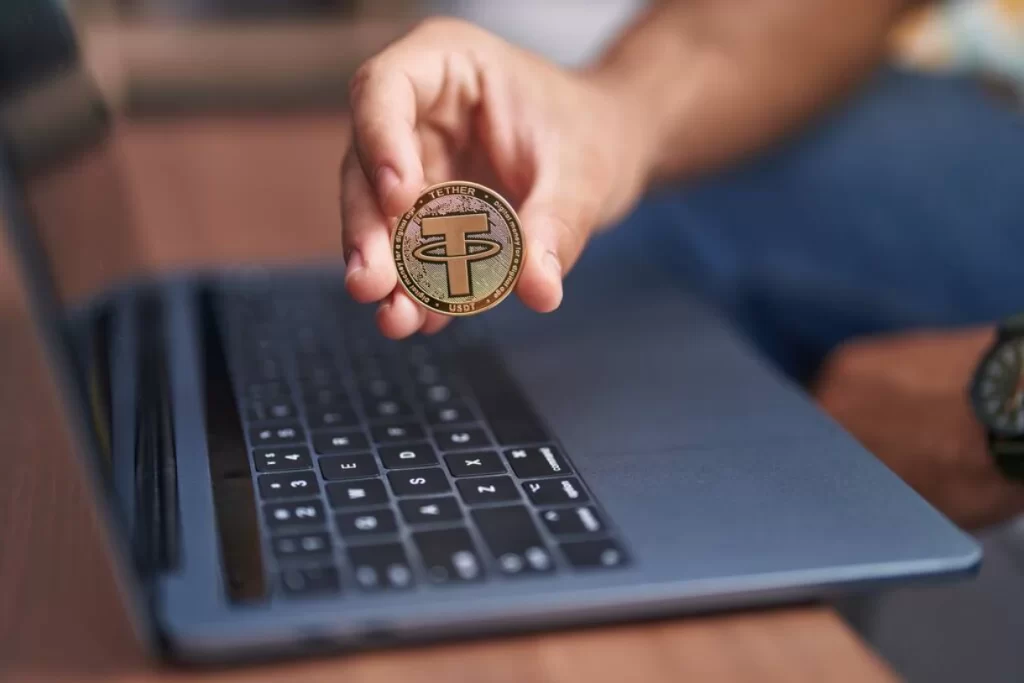 Holding a stablecoin next to a PC.